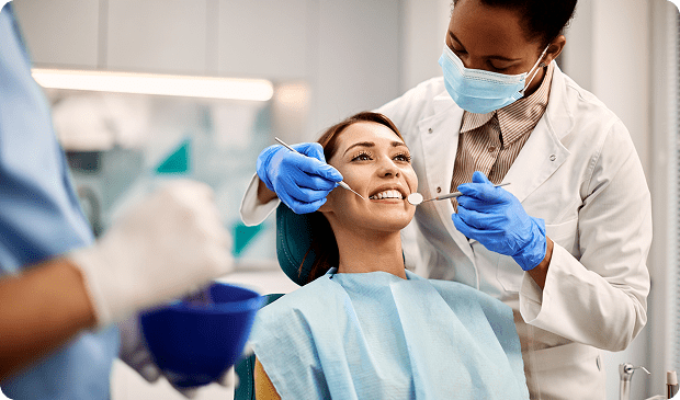 Dentist examining a patient's teeth, smiling.