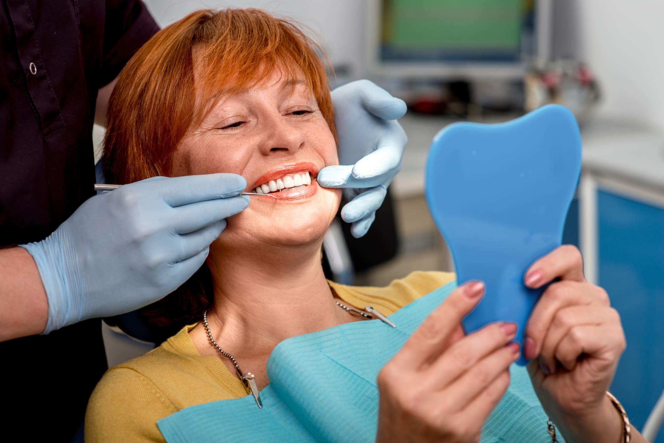 Woman smiling at dentist holding mirror.