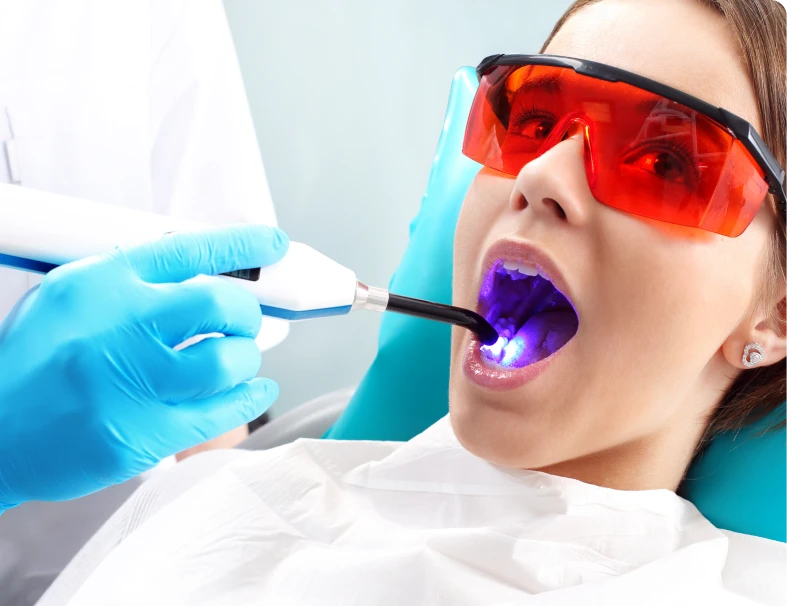 Patient receiving dental treatment with laser tool.