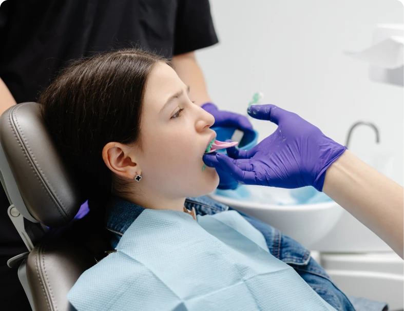 Patient receiving dental impression with purple gloves.