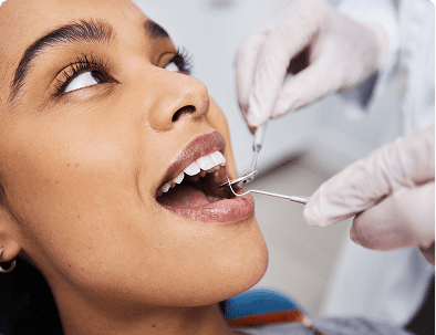 Woman receiving dental checkup with tools.