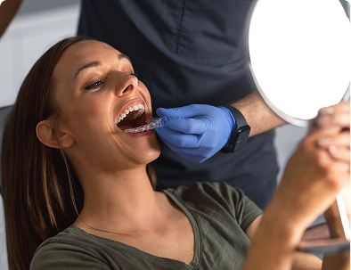 Woman receiving dental aligner with mirror reflection.