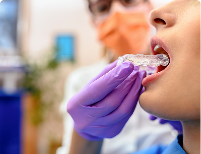 Dentist fitting clear aligner on patient.