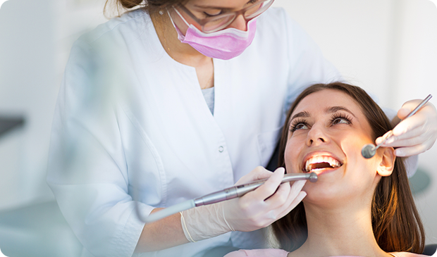Dentist examining a smiling patient’s teeth.