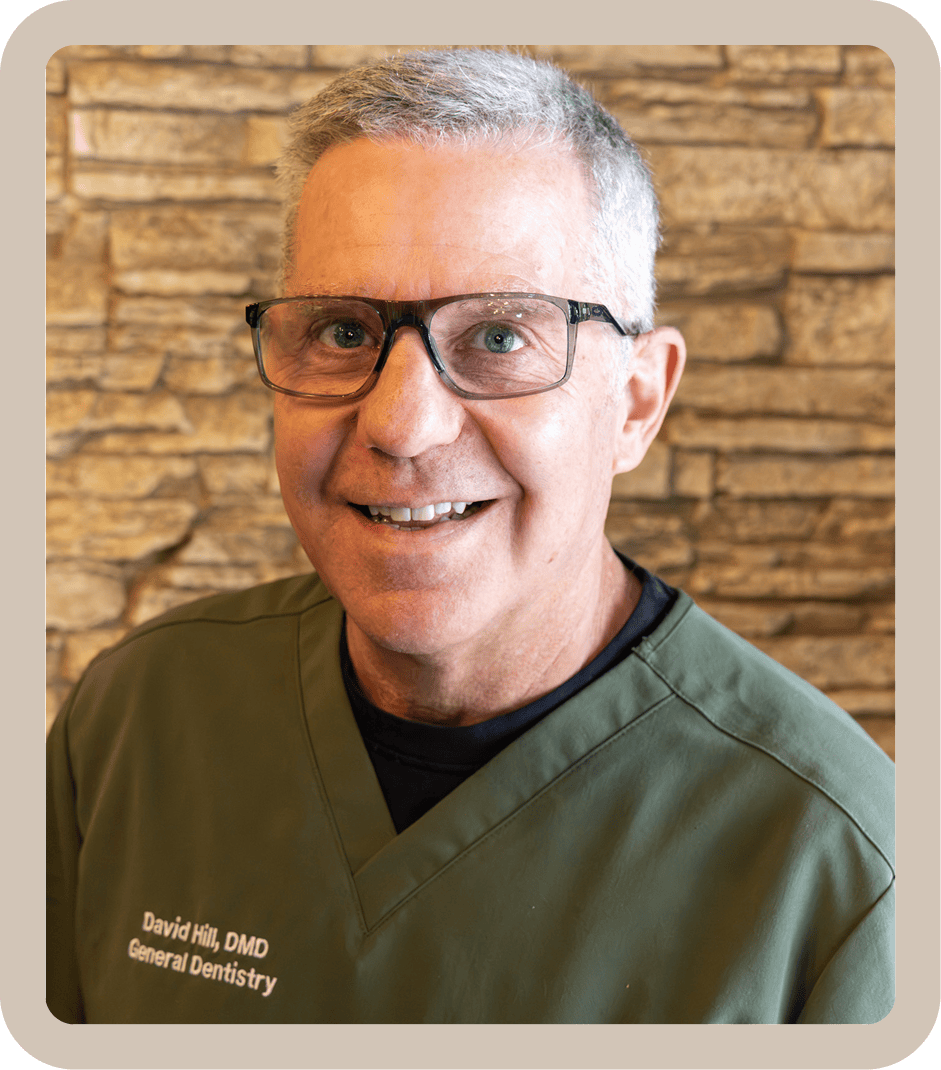 Smiling man in glasses and green scrubs.